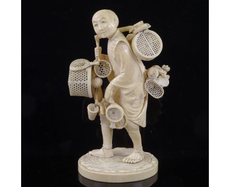 A Japanese ivory okimono of a basket seller, Meiji Period, with inset signed jade plaque under base, height 19cm 