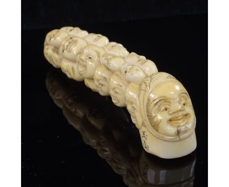 A Japanese ivory walking stick handle decorated with humorous faces, Meiji Period, signed, length 10cmThere is a very faint n