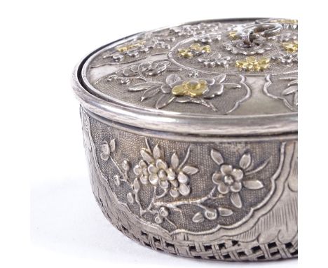 A Chinese unmarked silver cricket cage, circa 1900, parcel gilt relief decorated floral lid, and pierced lattice base, diamet