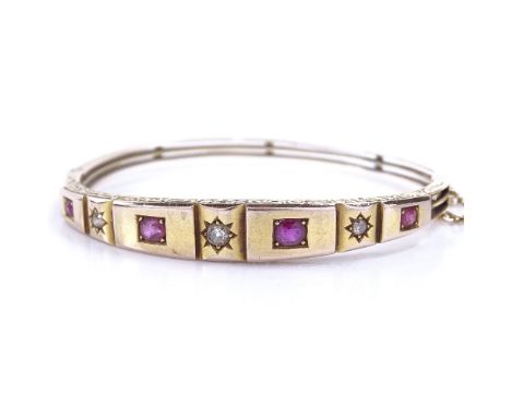 A Victorian unmarked gold 7-stone ruby and diamond hinged bangle, with foliate engraved bridge and openwork shank, setting he