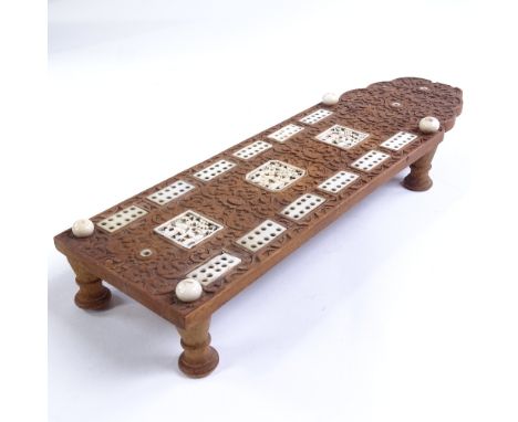 A Chinese 19th century relief carved wood games board, with inset carved ivory panels, on turned wood feet, length 24.5cmTher