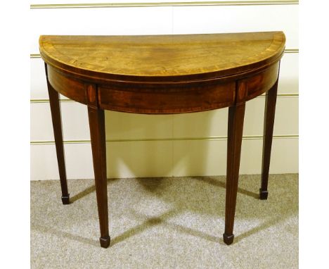 A George III mahogany demilune fold over card table, with tapered legs and spade feet 