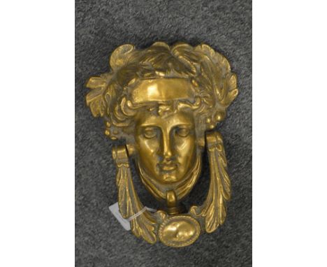 A polished cast brass Minerva’s head door knocker.