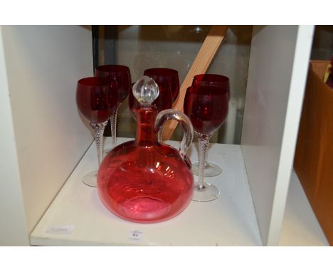 A cranberry glass claret jug and six ruby glass wine glasses.