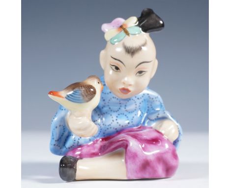 Marked Herend Hungary, this handpainted figurine features a seated child in traditional attire holding a small bird. The chil