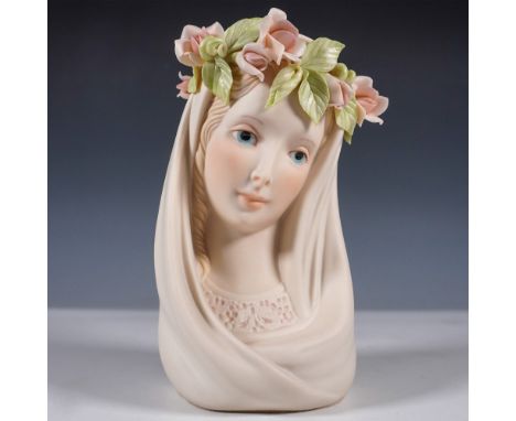 This delicate porcelain bust by Cybis depicts a serene Madonna with downcast eyes and a gentle smile, crowned with an intrica