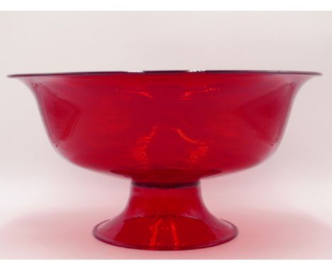 A LARGE RUBY GLASS FOOTED CENTRE BOWL WITH SWIRLED BLOWN DECORATION.    34CMS DIAMETER. 