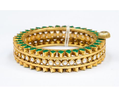 A Victorian style revival gilt metal bangle, comprising a central row of round half pearls within quatrefoil settings, with b