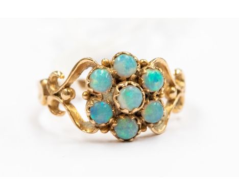 A Victorian opal cluster 9ct gold ring, comprising a flower cluster of round opals to open scroll shoulders, setting approx 1