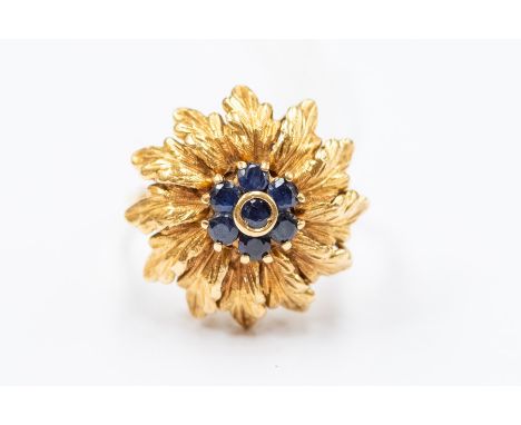 An 18ct gold and sapphire cocktail ring, comprising a dome of leaf decoration inset to the centre with a cluster of round cut