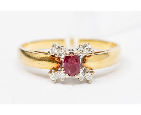 A ruby and diamond 18ct gold cluster ring, the central oval ruby approx. 4mm x 3mm, claw set within a cross of brilliant cut 