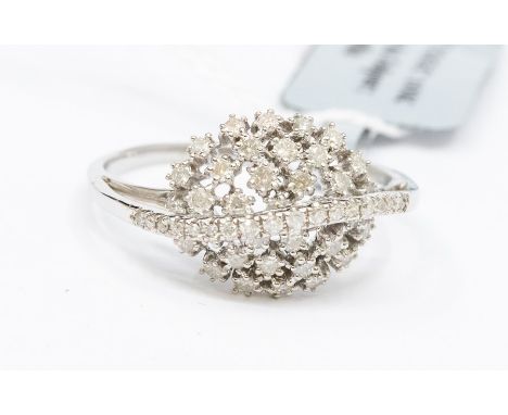 A diamond and 9ct white gold cluster ring, comprising a cluster dome set with claw set round brilliant cut diamonds, a sweep 