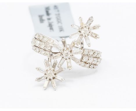 A diamond and 10ct white gold fancy dress ring, comprising three articulated daisy details each set with baguette cut diamond