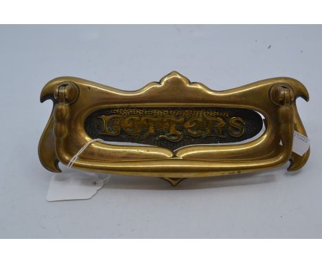 An Edwardian art nouveau brass door letter plate, circa 1900-1910, of double-scroll form, with shaped swing knocker handle, t