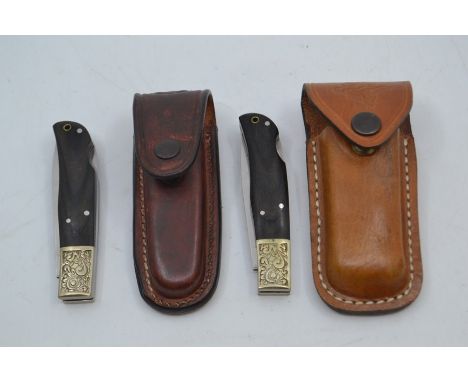 Two recent vintage Mauser folding pocket lock knives, with wood handles and 3.25" blades, each with an associated leather bel