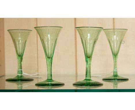 A set of four early 19th Century green glass sherry glasses, trumpet shaped with faceted bowls and stems (4)