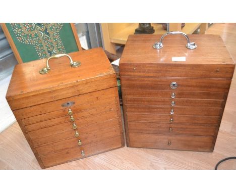Two mid 20th Century desktop watchmaker's cabinets, one in teak, the other walnut, each with a swing carry handle and hinged 