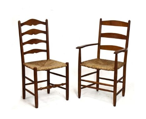 Late 19th Century golden oak Arts & Crafts rush seated ladder back armchair, the three rung back between out scrolled arms on