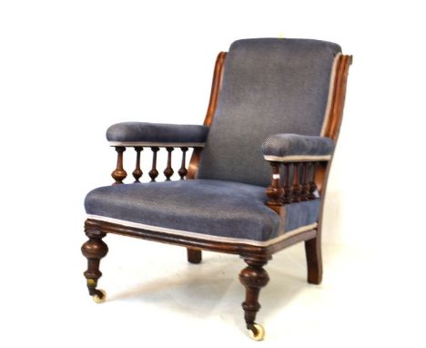 Victorian walnut framed easy chair having an over stuffed back between moulded uprights, the plain overstuffed arms on turned
