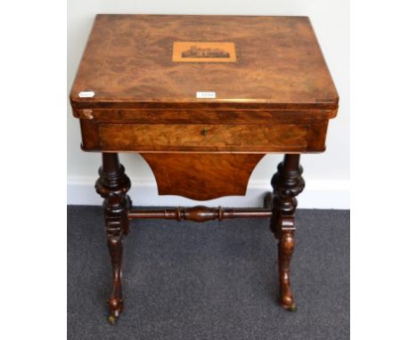 A Victorian Figured Walnut Games and Sewing Table, circa 1870, the hinged lid inlaid with a parquetry panel of an abbey, the 