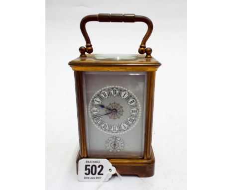 A brass carriage clock with an alarm feature with grey and gilt enamel dial      Clock appears to be working at time of inspe