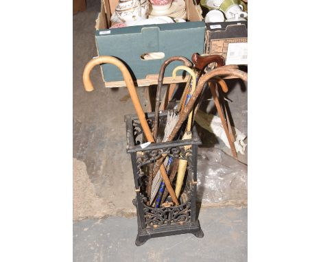 A Victorian cast iron stick stand and eight assorted walking sticks/umbrella's. 