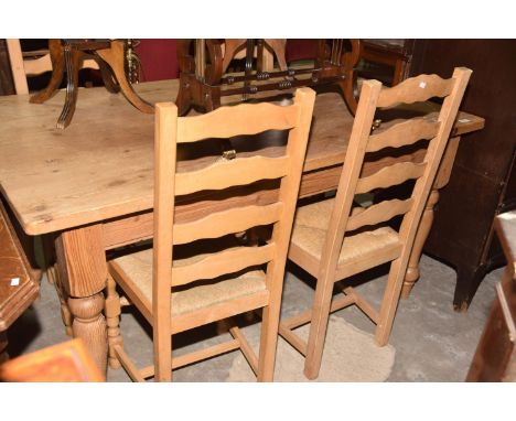 A Pine farmhouse kitchen table with a set of four rush seated ladder back kitchen chairs. 