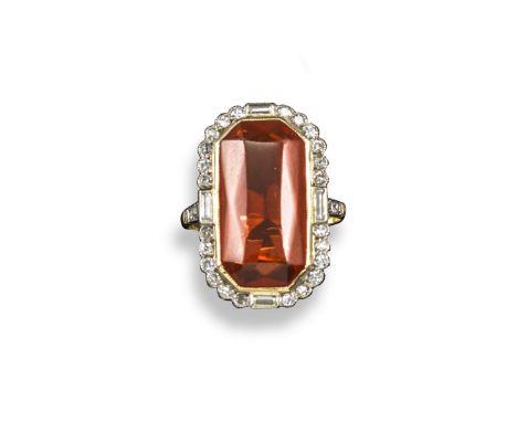 A fire opal and diamond cluster ring, the fancy-cut fire opal is set within a border of baguette-shaped and circular-cut diam