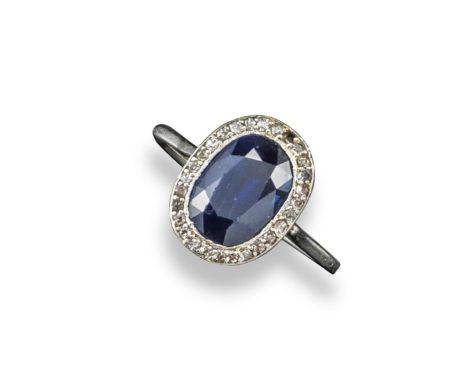 An early 20th century sapphire and diamond cluster ring, the oval-shaped sapphire is set within a surround of small cushion-s