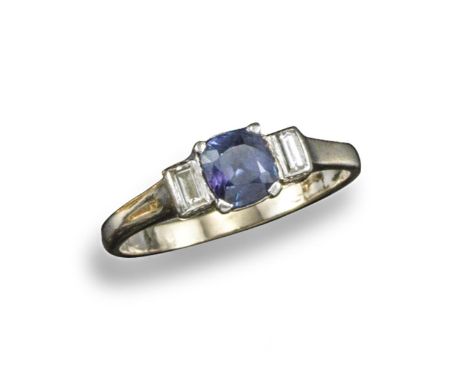 An alexandrite and diamond ring, the cushion shaped alexandrite is set either side with a baguette-shaped diamond in platinum