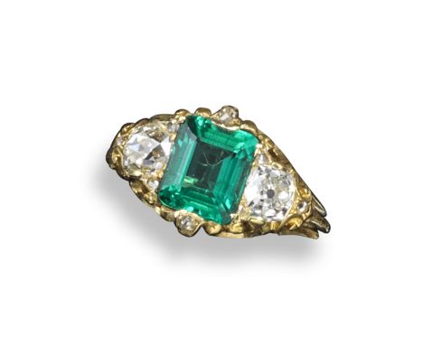 An emerald and diamond three stone ring, the emerald-cut emerald is set either side with an old cushion-shaped diamond in car