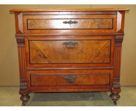 19th century walnut veneered commode of three long drawers, flanked by mock columns set on turned bun feet and ceramic castor