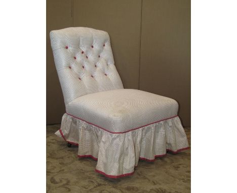 A low Edwardian bedroom or drawing room chair with upholstered seat and button back, raised on turned forelegs set on castors