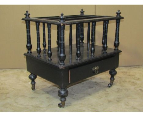A Victorian ebonised three divisional Canterbury with turned spindles over a drawer and turned supports with brass caps and c