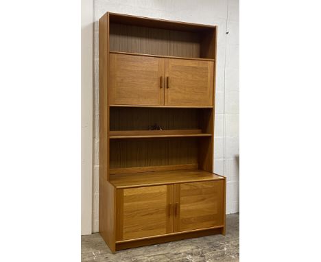 A mid century teak bookcase cabinet, fitted with two cupboards above an illuminated shelf, the base having twin cupboard door