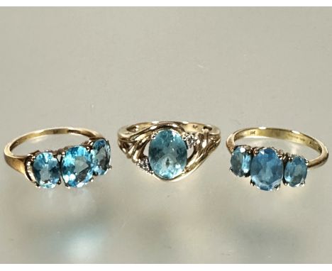 A collection of three 9ct gold blue zircon set rings including two three stone graduated rings and an oval cut solitaire ring