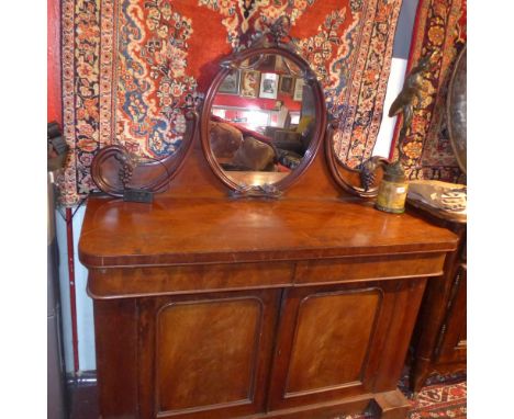 A Victorian mahogany chiffonier, the oval mirror with carved grape and vine detail over two cupboard doors, H:160cm W:134cm D