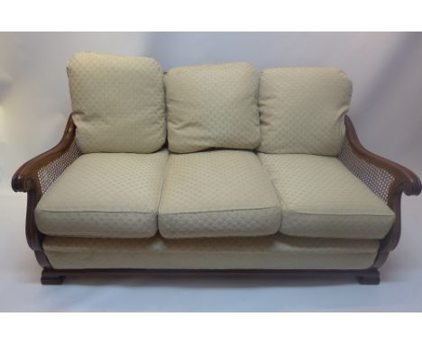 An early 20th Century mahogany two seater bergere sofa with blue upholstered raised on block feet