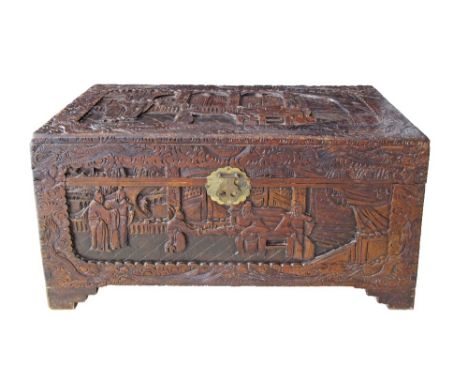A Chinese carved camphor wood chest / trunk, with a brass clasp to the front. The chest is raised on four step shaped feet an