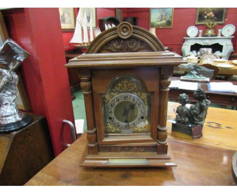 An early 20th Century walnut bracket clock of architectural form with bras dial and silvered Arabic chapter ring, with presen