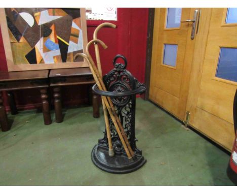 A Victorian style cast iron stick stand and three walking sticks