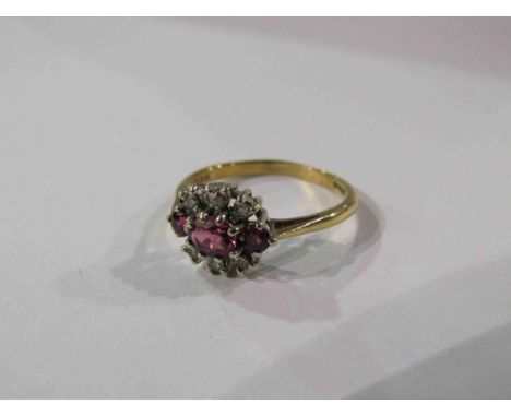 A 9ct gold ring set with three rubies enclosed by six individually set diamonds. Size O/P, 2.4g