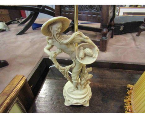An Oriental figural lamp with silk tasselled shade