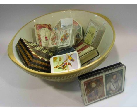 A mixing bowl containing vintage packs of playing cards, travelling chess etc.