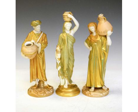 James Hadley for Royal Worcester - Pair of shot enamel porcelain figures modelled as male and female water carriers, dressed 