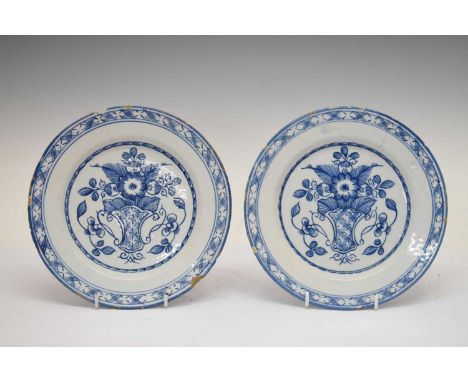 Two late 18th century English delftware plates, each painted basket of flowers within stylised border, 22.5cm diameter