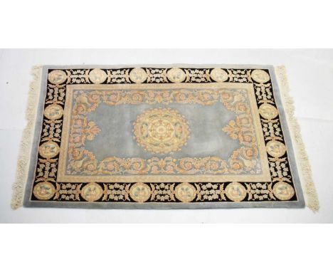 Chinese Kyan light blue ground wool rug with central medallion and black outer border, 244cm x 163cm wide 