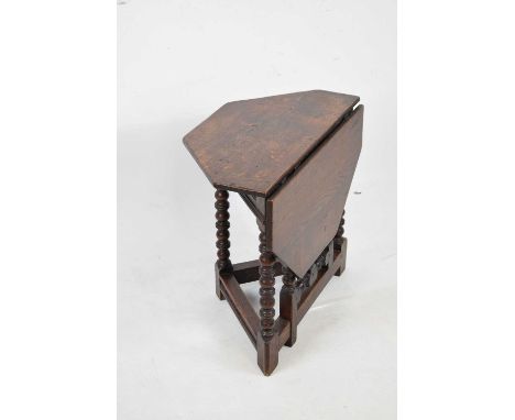 Small oak 'credence' style occasional table, the top opening to octagonal form on bobbin-turned gateleg and supports with cha