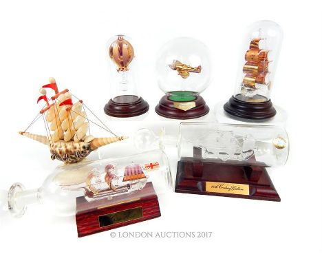 A collection of model boats including one made from sea shells, two hand blown glass boats in bottles, another hand blown boa