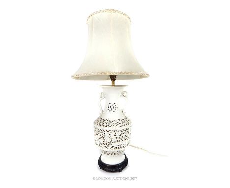 A Chinese Blanc de Chine porcelain table lamp with shade, having twin Ruyi design handles and a pierced body decorated with f